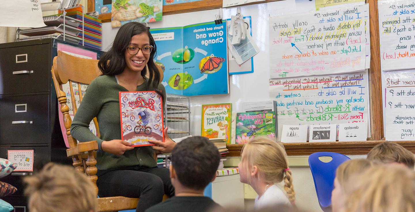 MSU Denver student Idalee Nunez reading a book to young children in a classroom.